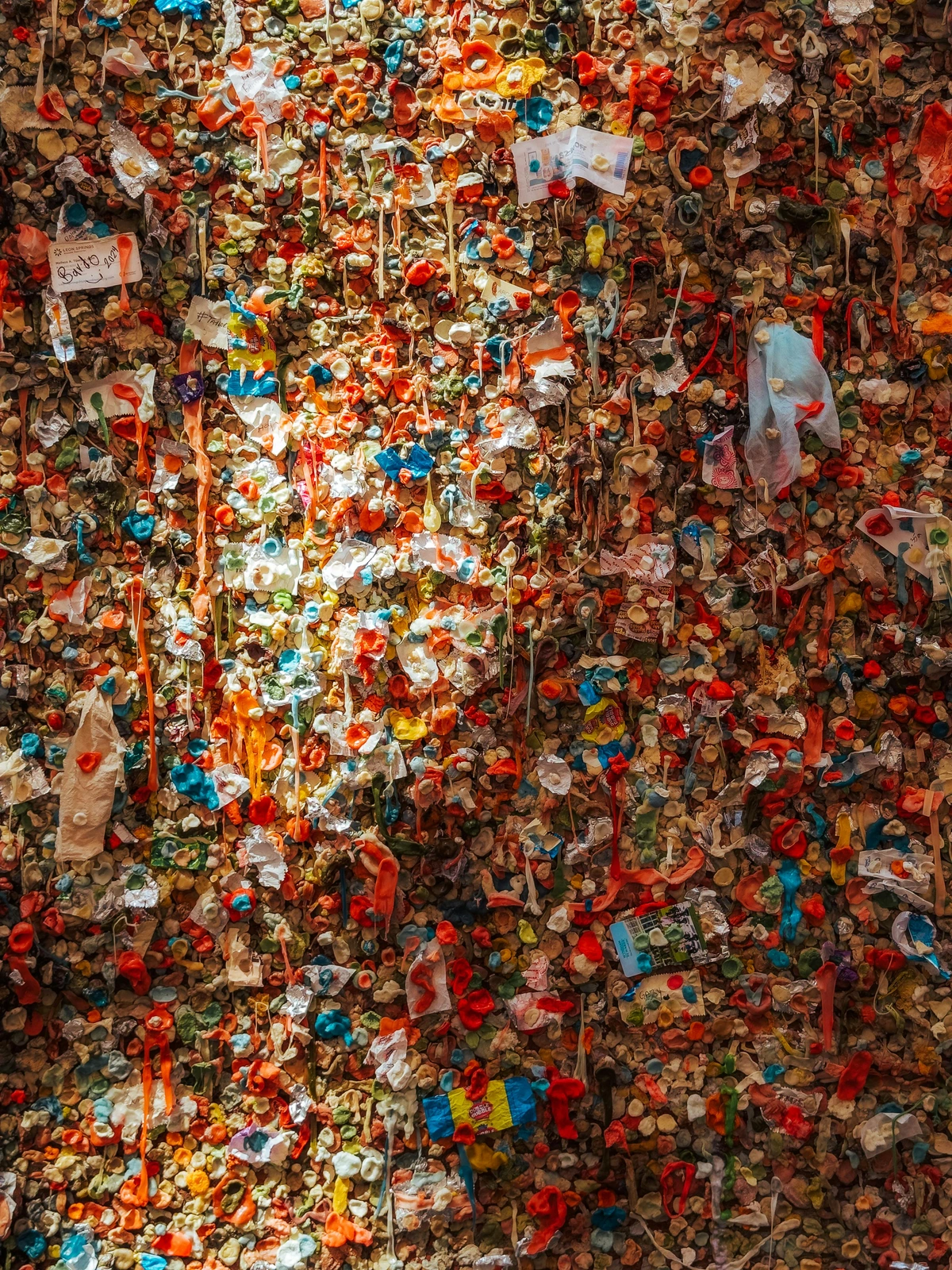 Photo of the gum wall in Seattle, Washington, USA, where thousands of different coloured, chewed wads of gum have been stuck, completely covering the surface.