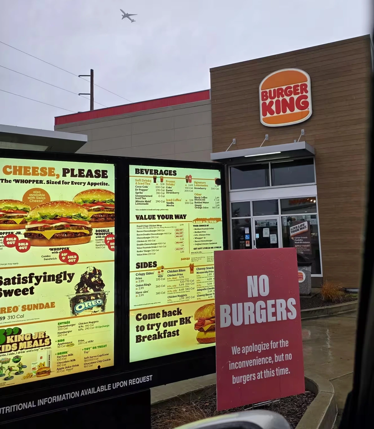 a picture of a burger king drive through - there is a sign posted that states they have no burgers